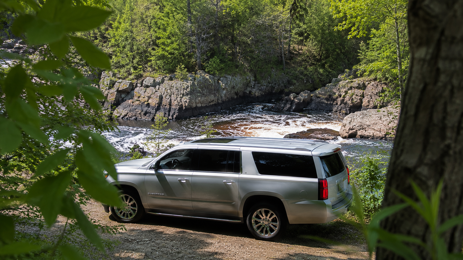 Silver luxury SUV limo parked near a rocky river gorge in Eganville.