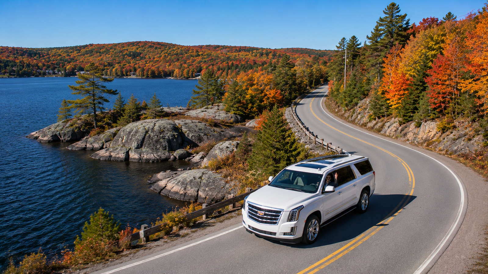 White executive SUV limo parked near a rocky lake shore in Huntsville.